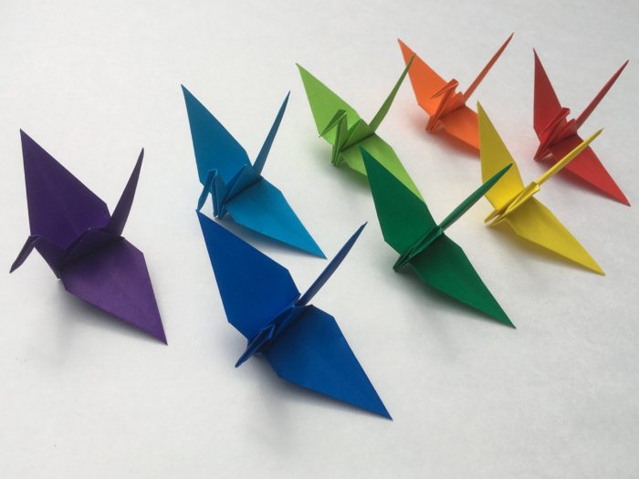 Eight origami cranes in rainbow colors