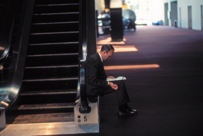 Collins sits alone next to escalator studying papers