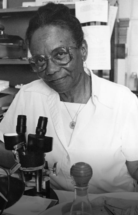 Black and white photo of woman at microscope