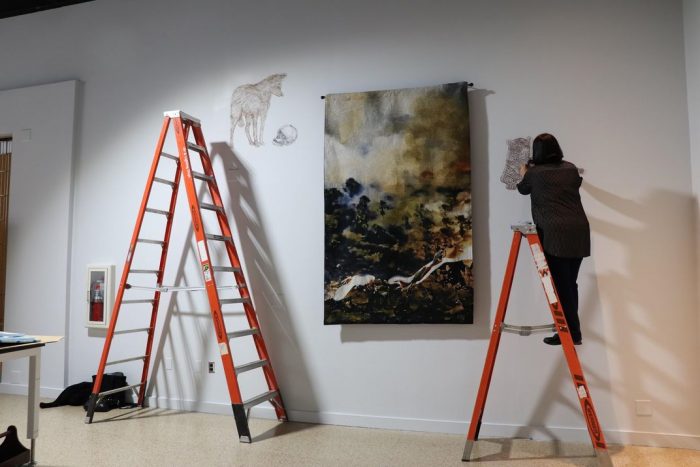 Artist on ladder working in gallery