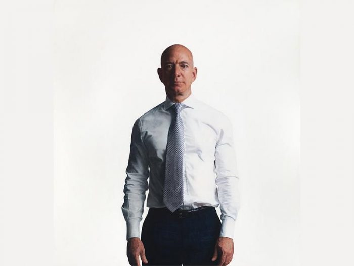 Jeff Bezos, in shirt and tie, poses against white background