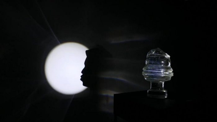 Glass sculpture that casts shadow of human profile