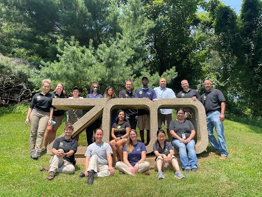 AZoo professionals posing in front of Zoo sign