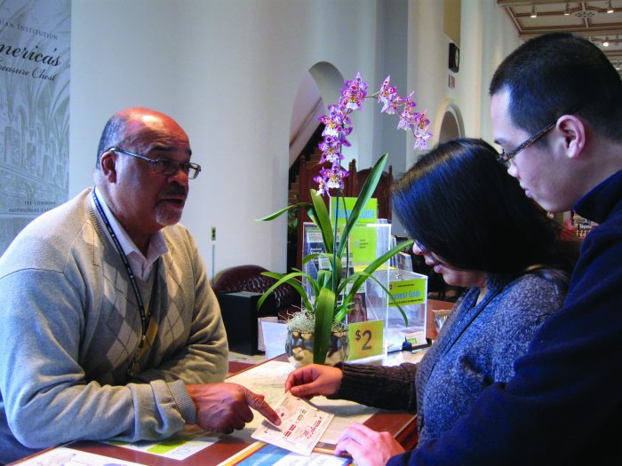 Volunteer Albert R. Howard greets visitors Jona Golbin and Oliver Banzon and provides information on the Smithsonian and locations of its museums at the Smithsonian Information Center in the Castle.