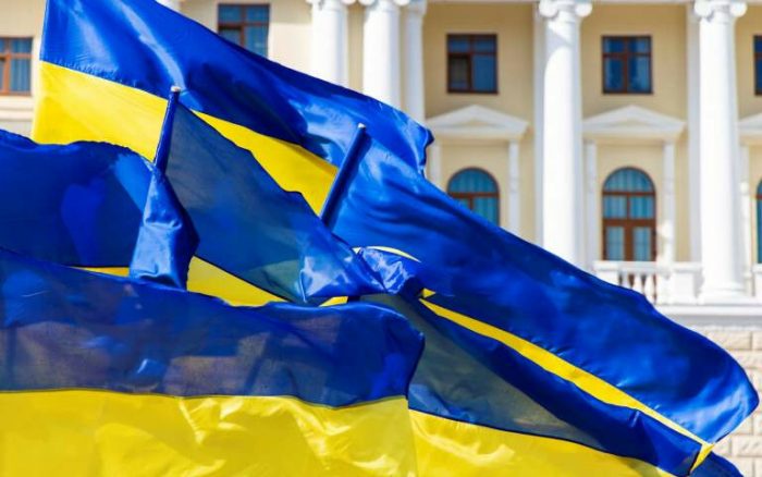 Blue and yellow flags in foreground of government buildin