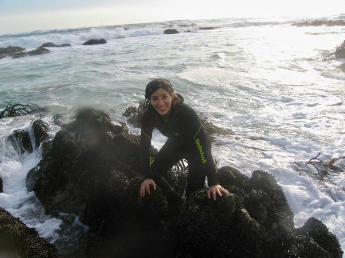 Pappalardo in wet suit climbing on ocean rocks