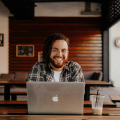 Stock photo of smiling bearded man with Apple laptop