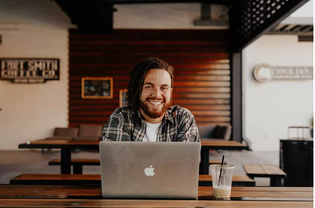 Stock photo of smiling bearded man with Apple laptop