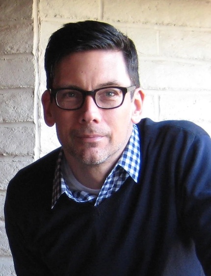 Head shot of Griffey wearng glasses, blue-checked shirt and dark sweater