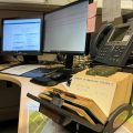 Rolodex with index cards in foreground, computer monitors in background