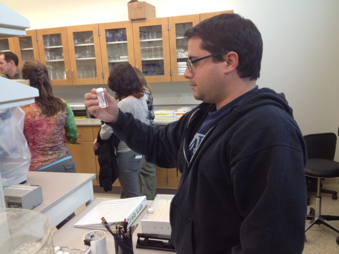 Rob Aguilar examines vial in SERC lab