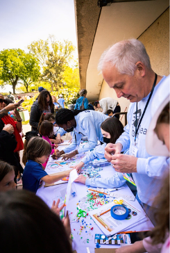 Children and adult volunteers work at circuitry table