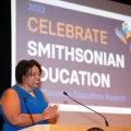 Dr Chism on stage with "Celebrate Smithsonian Education" on screen behind her
