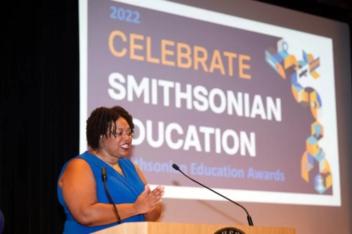 Dr Chism on stage with "Celebrate Smithsonian Education" on screen behind her