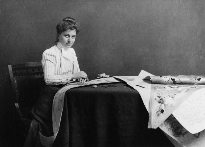 Black and white photo of Temple looking up from her desk