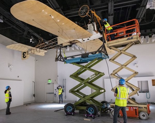 Workers with upside-down plane on lift