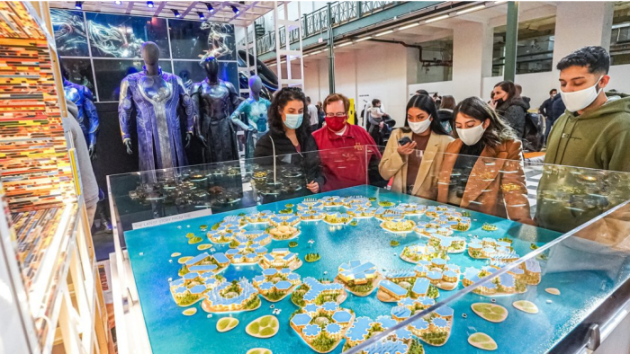 Masked visitors around display case at FUTURES exhibition