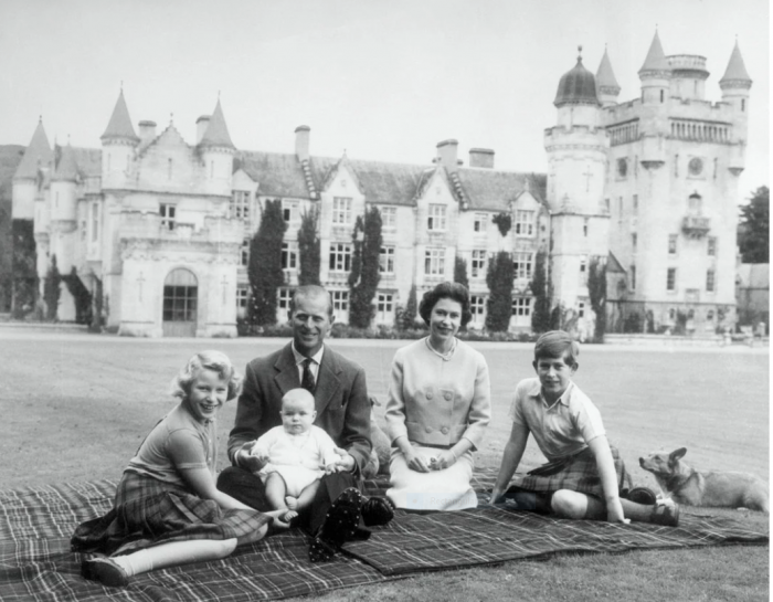 Black and white photo of Queen and Prince Philip with children, castle in background