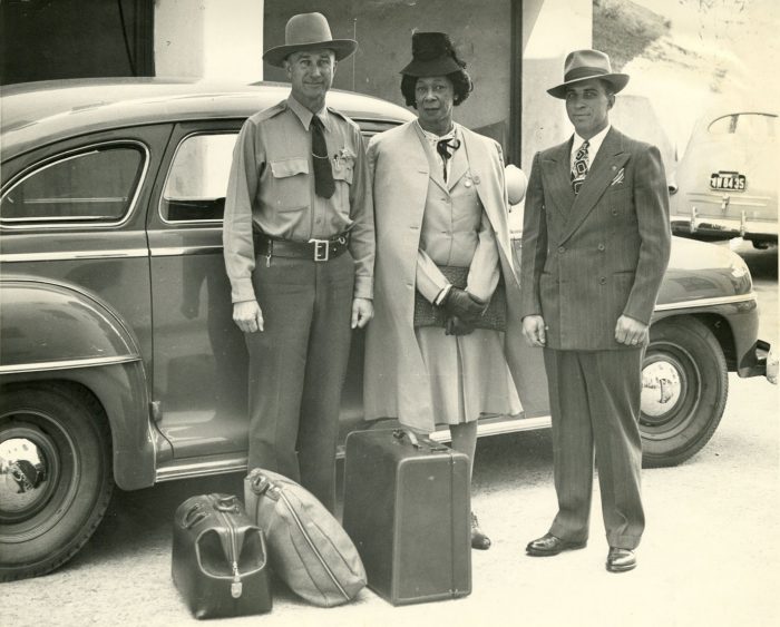 Black and white photo of Lucy Hicks Anderson standing beside car between two deputies