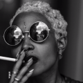 Screenshot of woman wearing sunglasses and smoking a cigarette