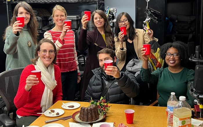 From left to right: Tami O’Neill, Ashley Rose Young, Lizzie Peabody, Jess Sadeq, James Morrison, Ann Conanan, and Nathalie Boyd raise red Solo cups in a toast. 