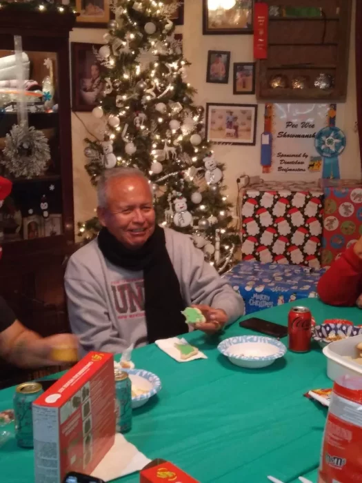 Duane Harris eats a cookie with Christmas tree and gifts in the background