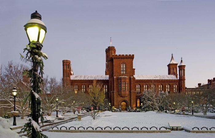 Rear of Smithsonian Castle in Haupt Garden with snow on the ground, torchlightin foreground