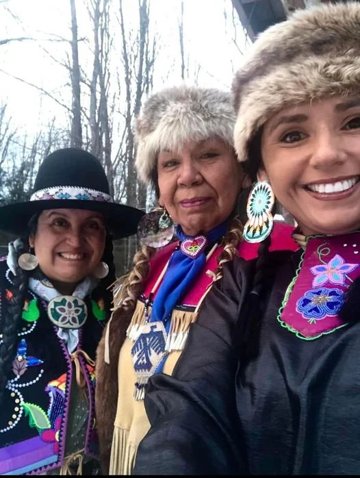 Three women in colorful native dress and fur hats