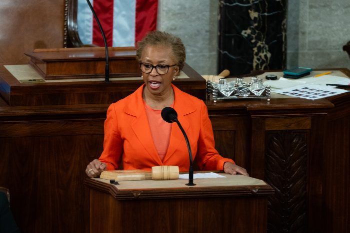 Cheryl Johnson in orange suit at podium