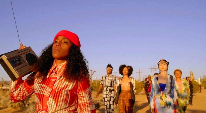 Women of color follow a Black woman carrying a boombox