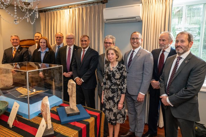 Group shot of guests gathered around table displaying artifacts