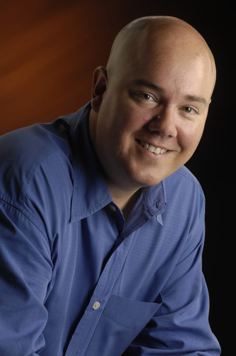 Headshot of Ed Tudor wearing blue shirt