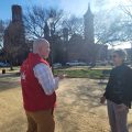 Volunteer in red vest speaks to passerby on the National Mall