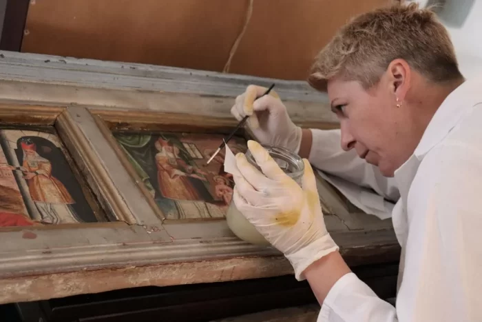 Curator works on damaged painting