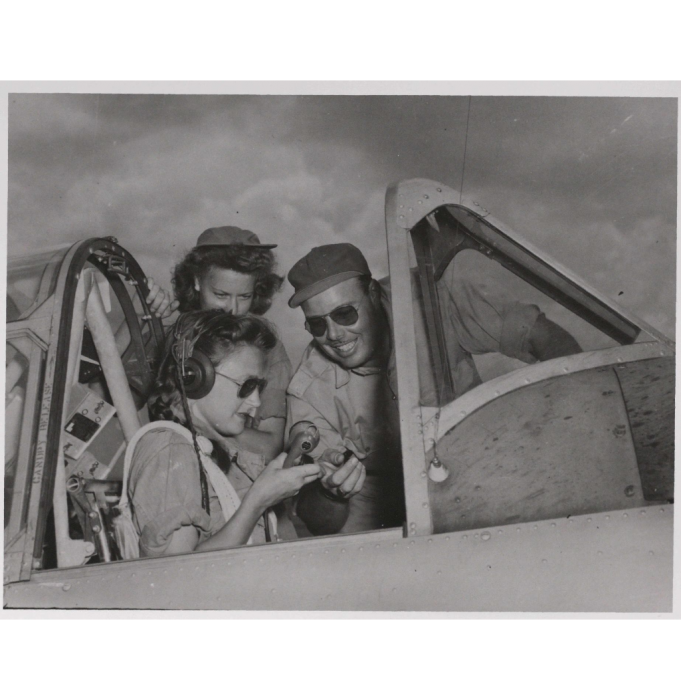 WASP pilot in the cockpit of plane with male technician checking equipment