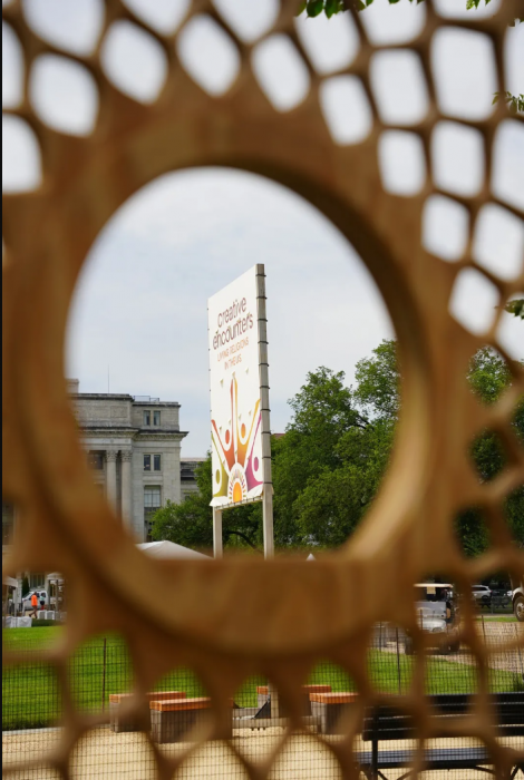 Photo of Creative Encounters sign framed by wooden circle in foreground