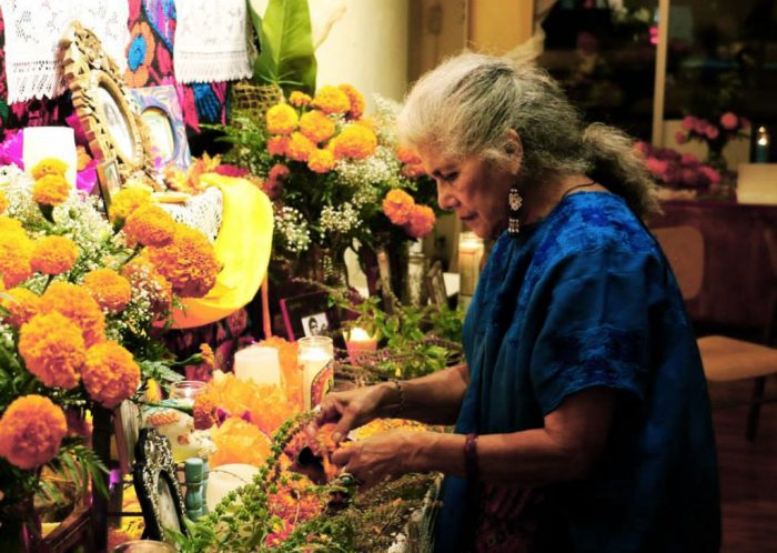 Older woman in blue dress working at flower-bedecked altar