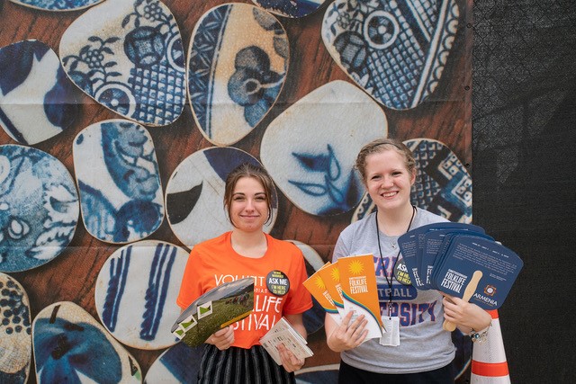 Folklife Festival volunteers holding fans and brochures