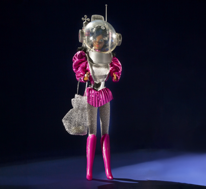 Dark-skinned Barbie doll in silver and pink outfit including fishbowl helmet and boots