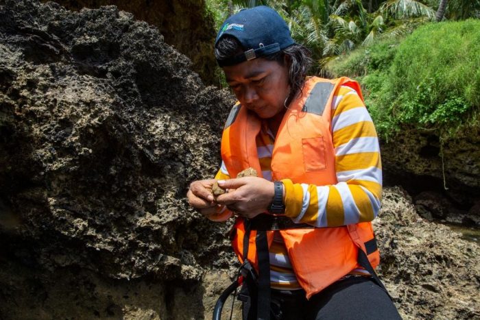 Researcher in orange reflective vest examines otolith sample