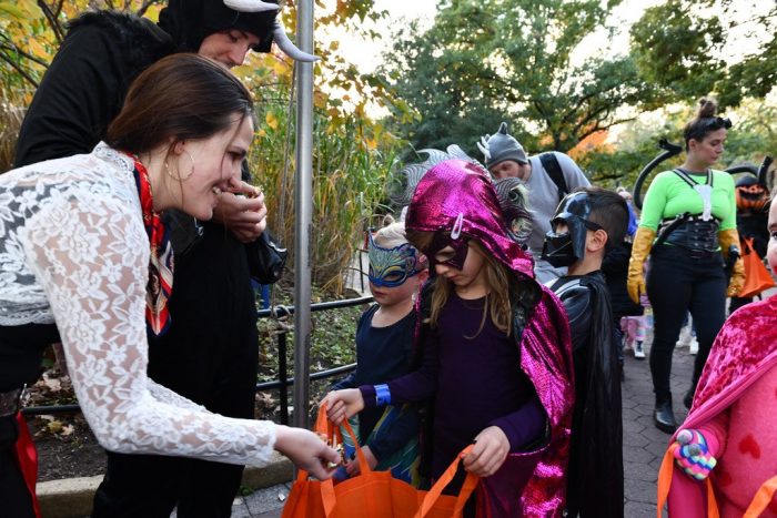 volunteers give treats to costumed children at the Zoo