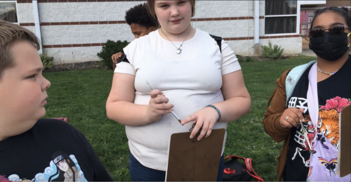 Small group of students and teacher holding clipboards