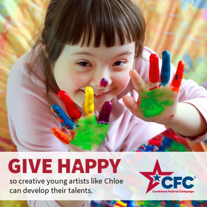 Child with Down Syndrome happily displays her hands covered with fingerpaint