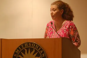 Brigitte Blachère standing at podium with Smithsonian seal