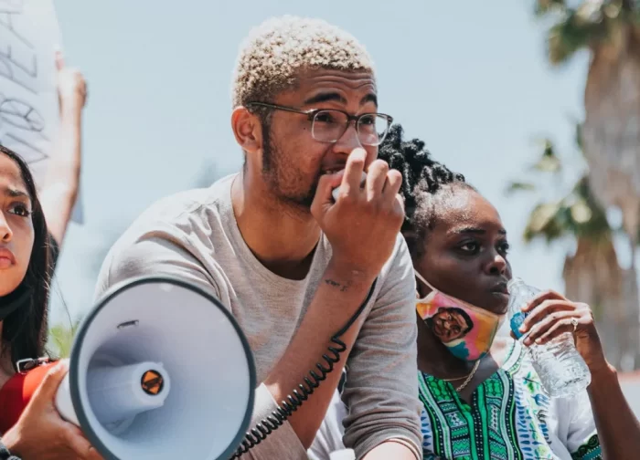 Three students of color, one speaking into a megaphone