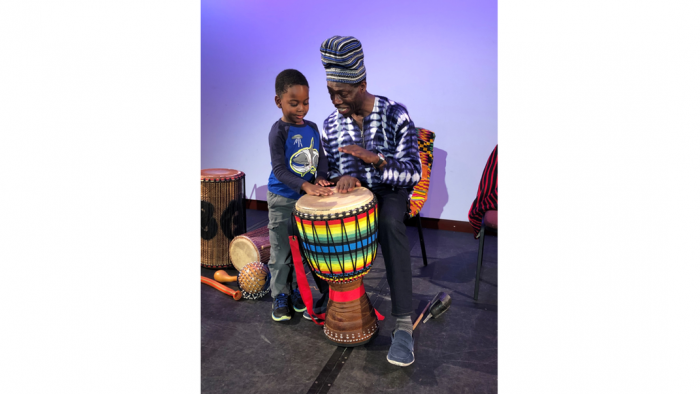 African drummer demonstrates for child