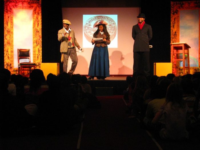 Performers on stage; darkened audience in foregound