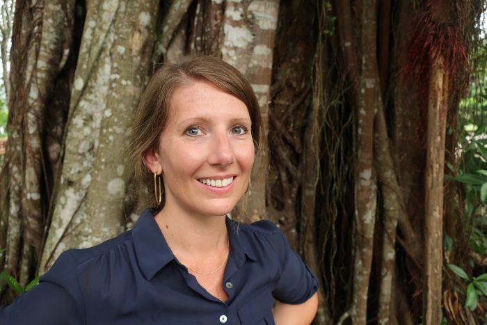 Erin Spear poses in the field against a backdrop of tropical trees