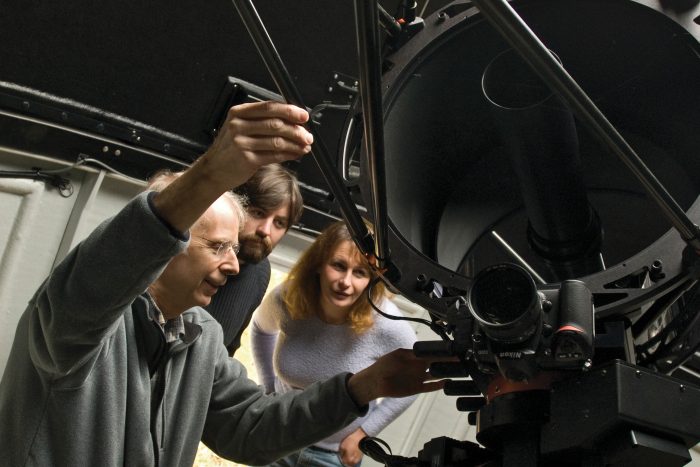 Collins and two others examine telescope