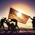 Soldiers raising American flag, seen in silhouette